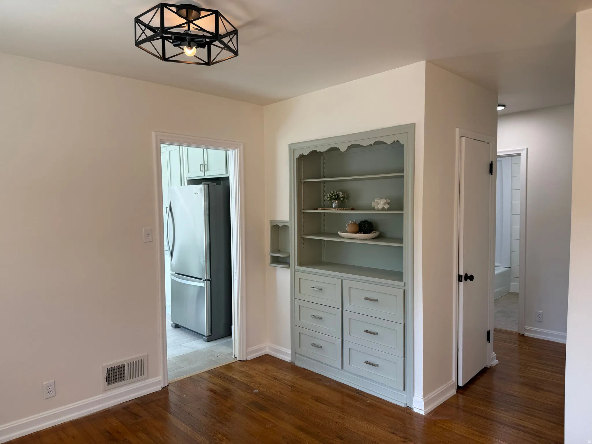 Hardwood flooring throughout featuring a built-in cabinetry unit with shelving and drawers