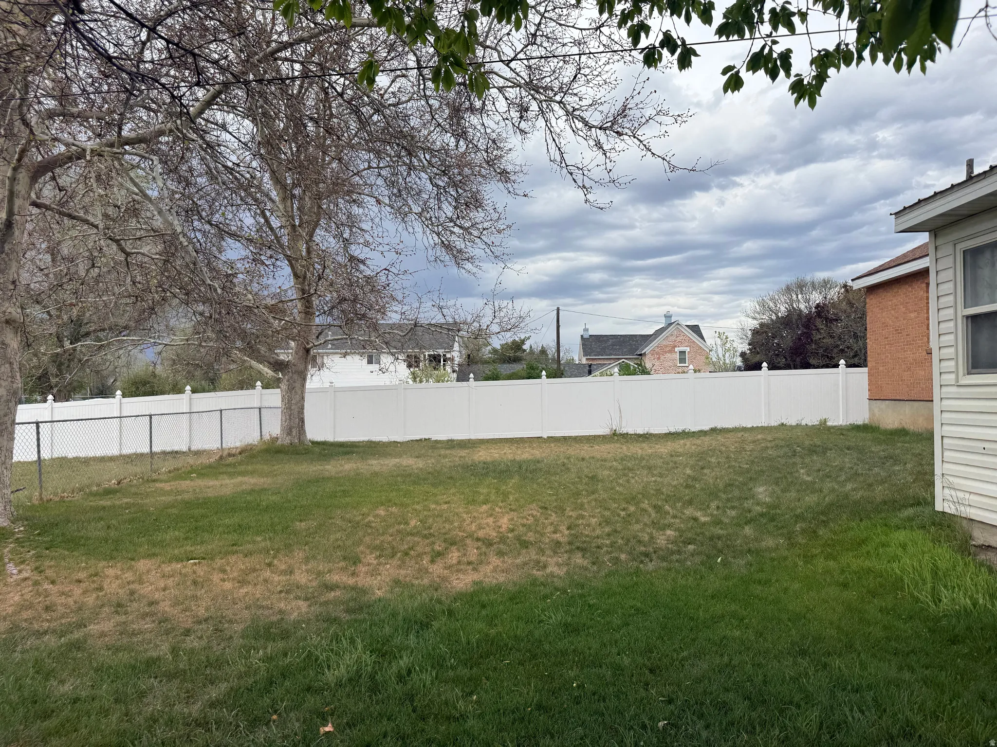 Spacious backyard featuring a white vinyl privacy fence and chain link fencing