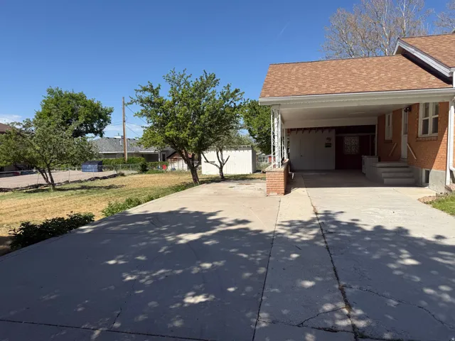 Brick exterior with a covered carport, concrete driveway, and concrete steps leading to the entry