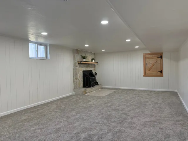 Spacious room featuring plush gray carpeting, white vertical plank walls, and recessed lighting