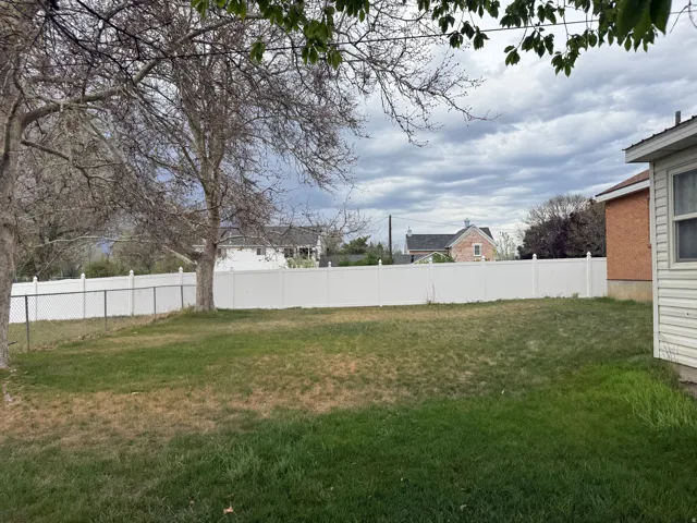 Spacious backyard featuring a white vinyl privacy fence and chain link fencing
