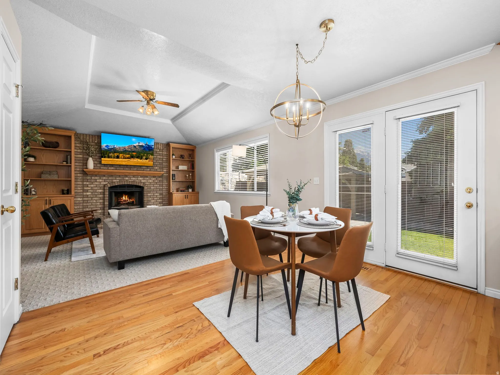 Hardwood flooring extending from the dining area to a living space featuring a brick fireplace flanked by built-in shelving