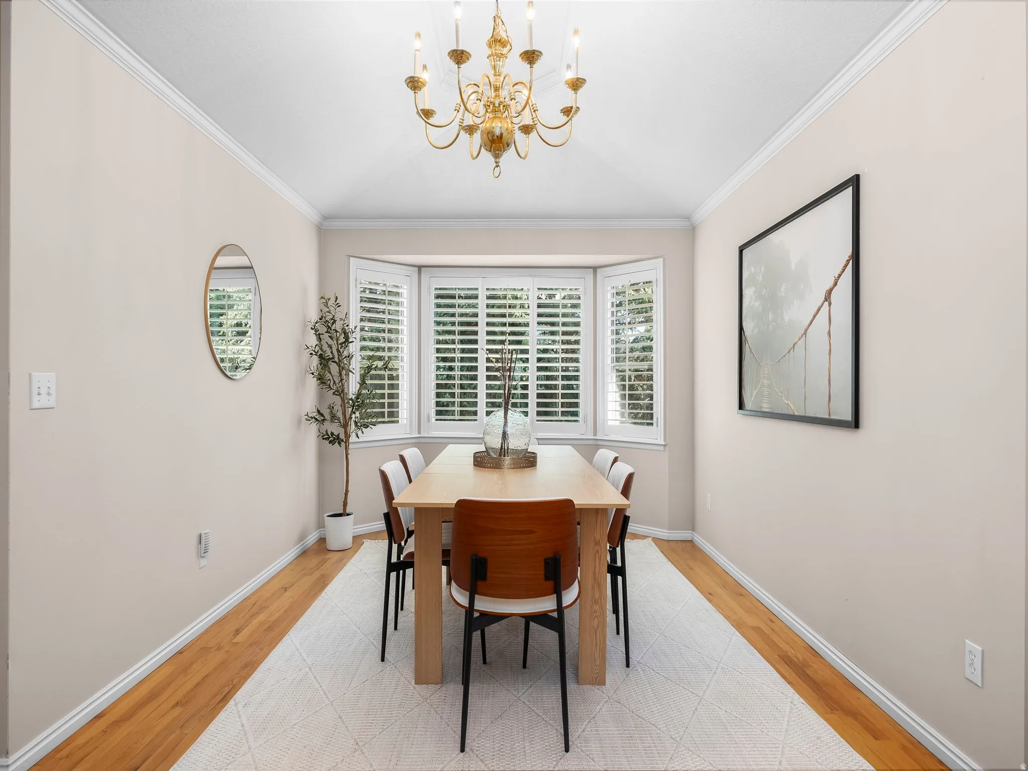 Dining area featuring a gold-toned chandelier, crown molding, and wood-finish flooring