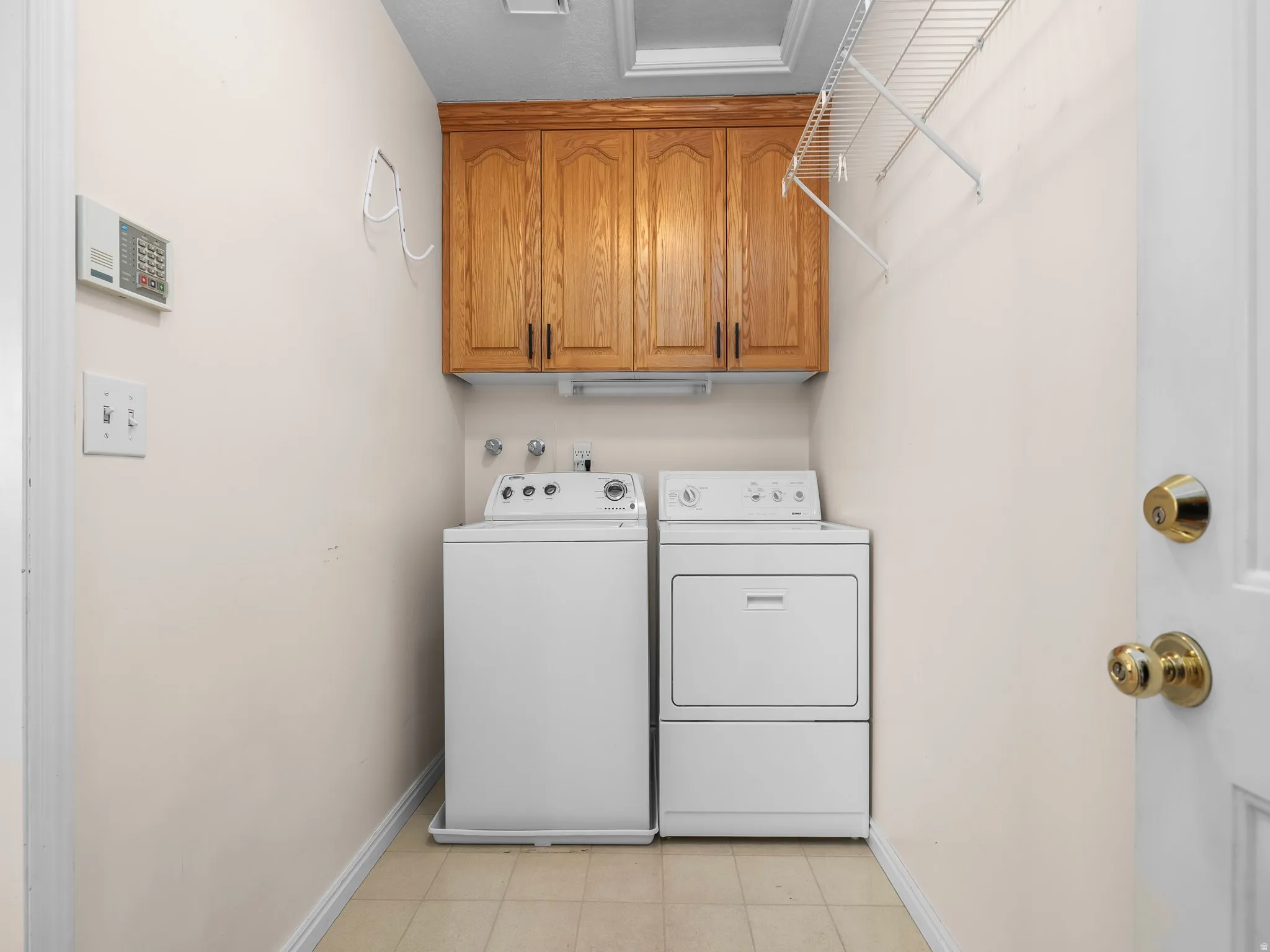 Laundry area featuring upper wood cabinetry, white appliances, and wire shelving