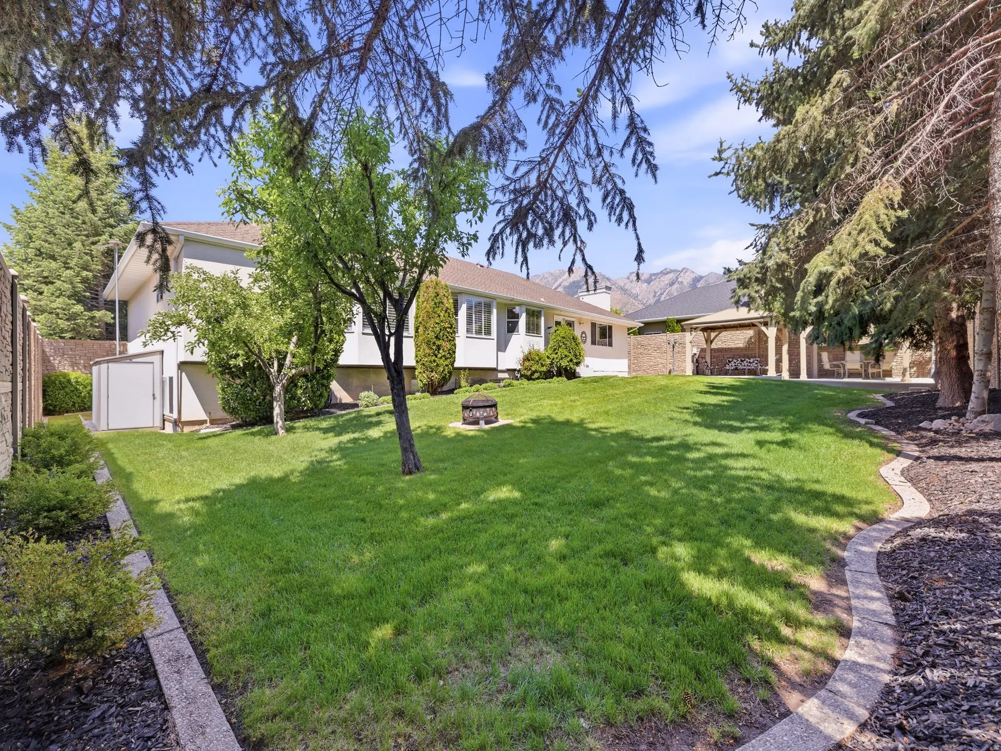 Expansive lawn space featuring mature trees and established landscaping beds