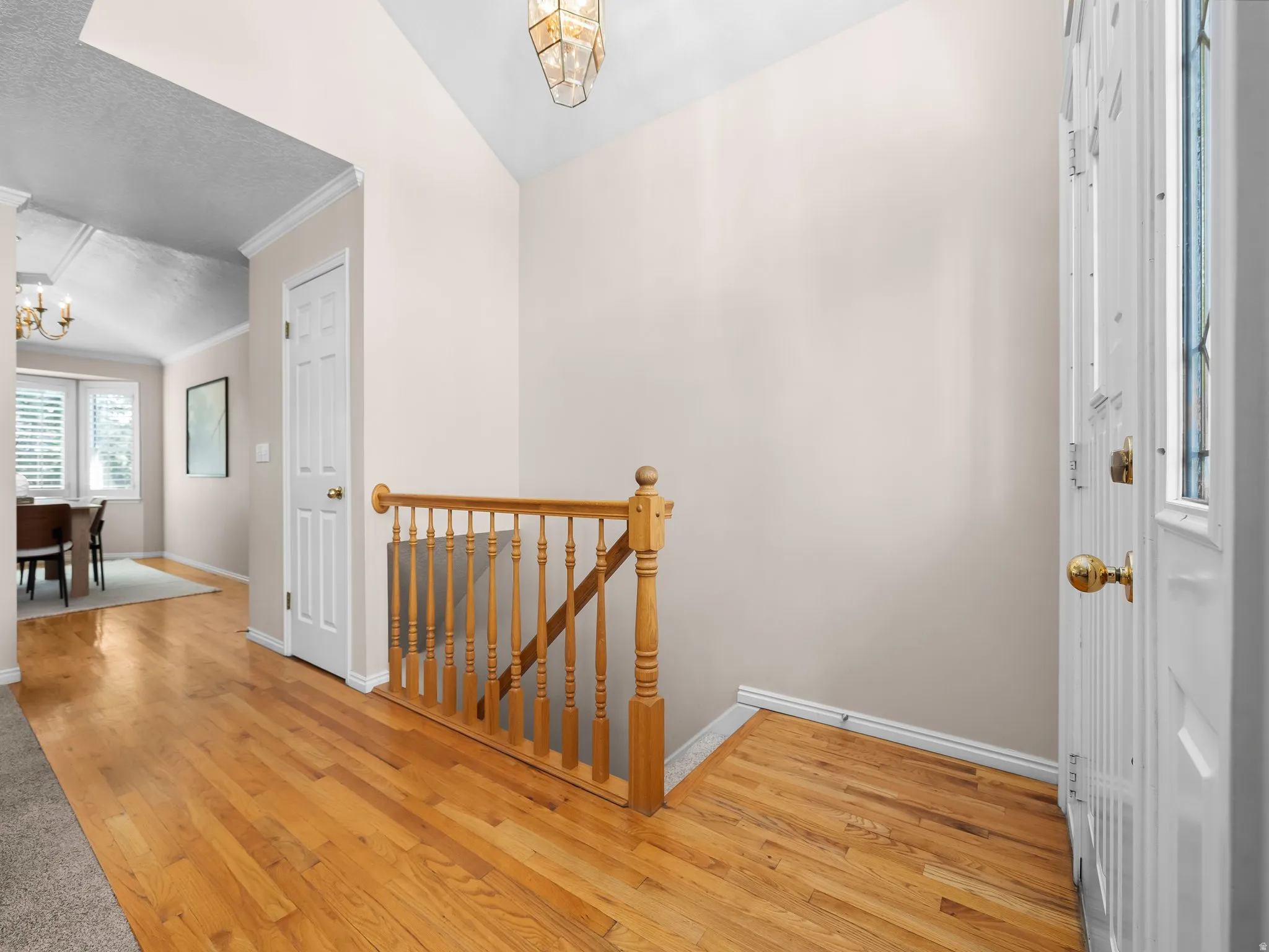 Entryway featuring hardwood flooring, a natural wood staircase railing, and a decorative ceiling light fixture