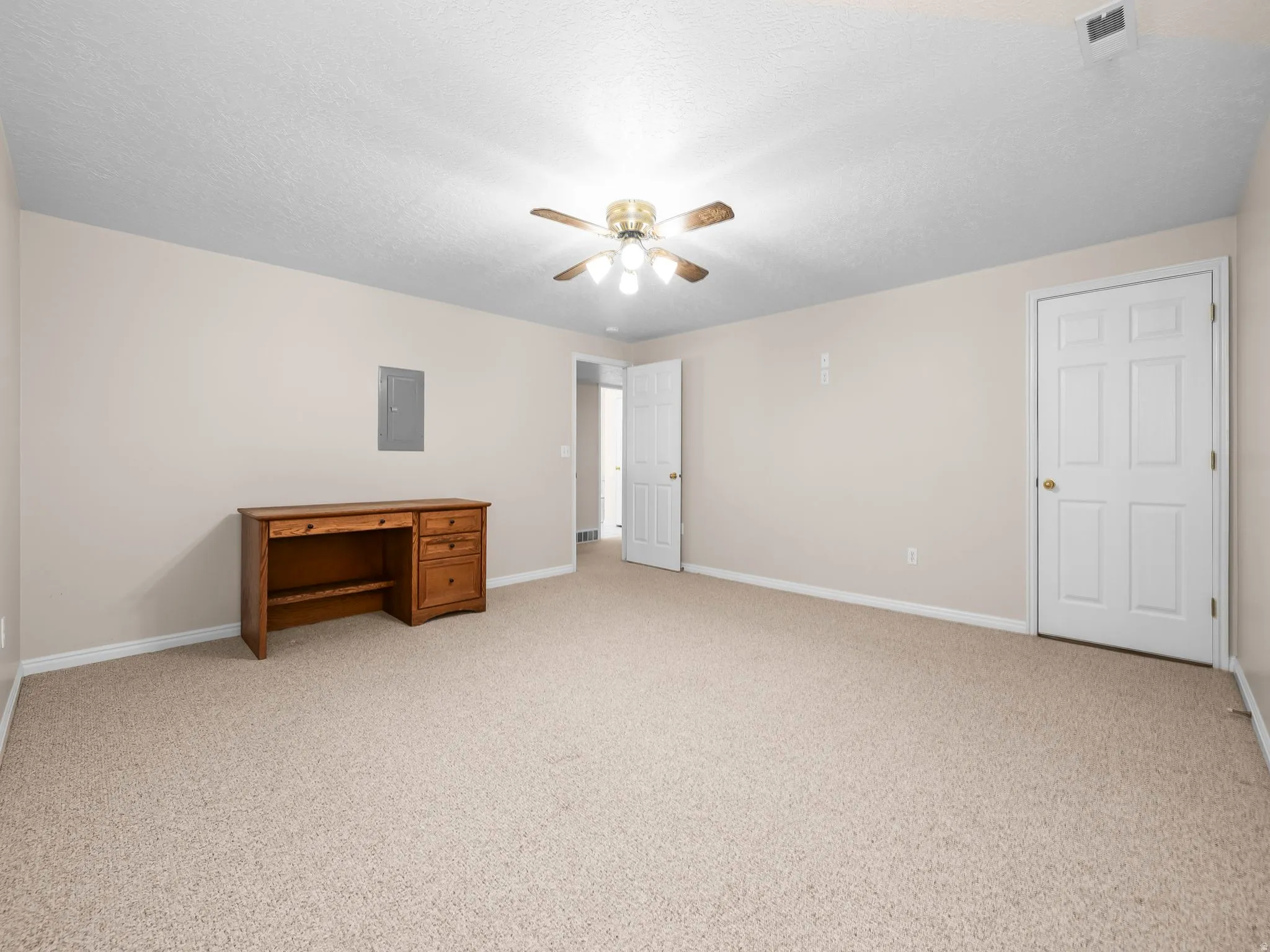 Spacious room featuring neutral carpeting, light-toned walls, and a ceiling fan with integrated lighting
