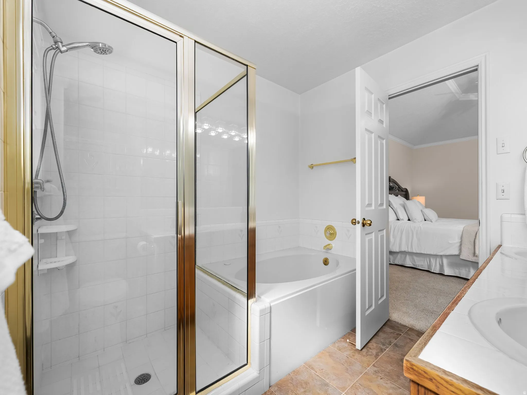 Bathroom featuring a shower with a gold-framed glass enclosure, white tile surround, and a built-in shelf