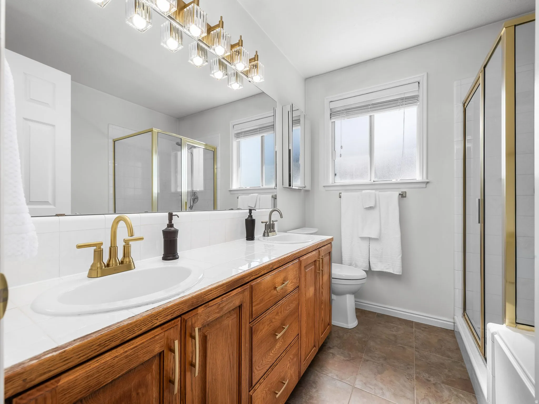 Double vanity with wood-finish cabinetry and white tile countertop