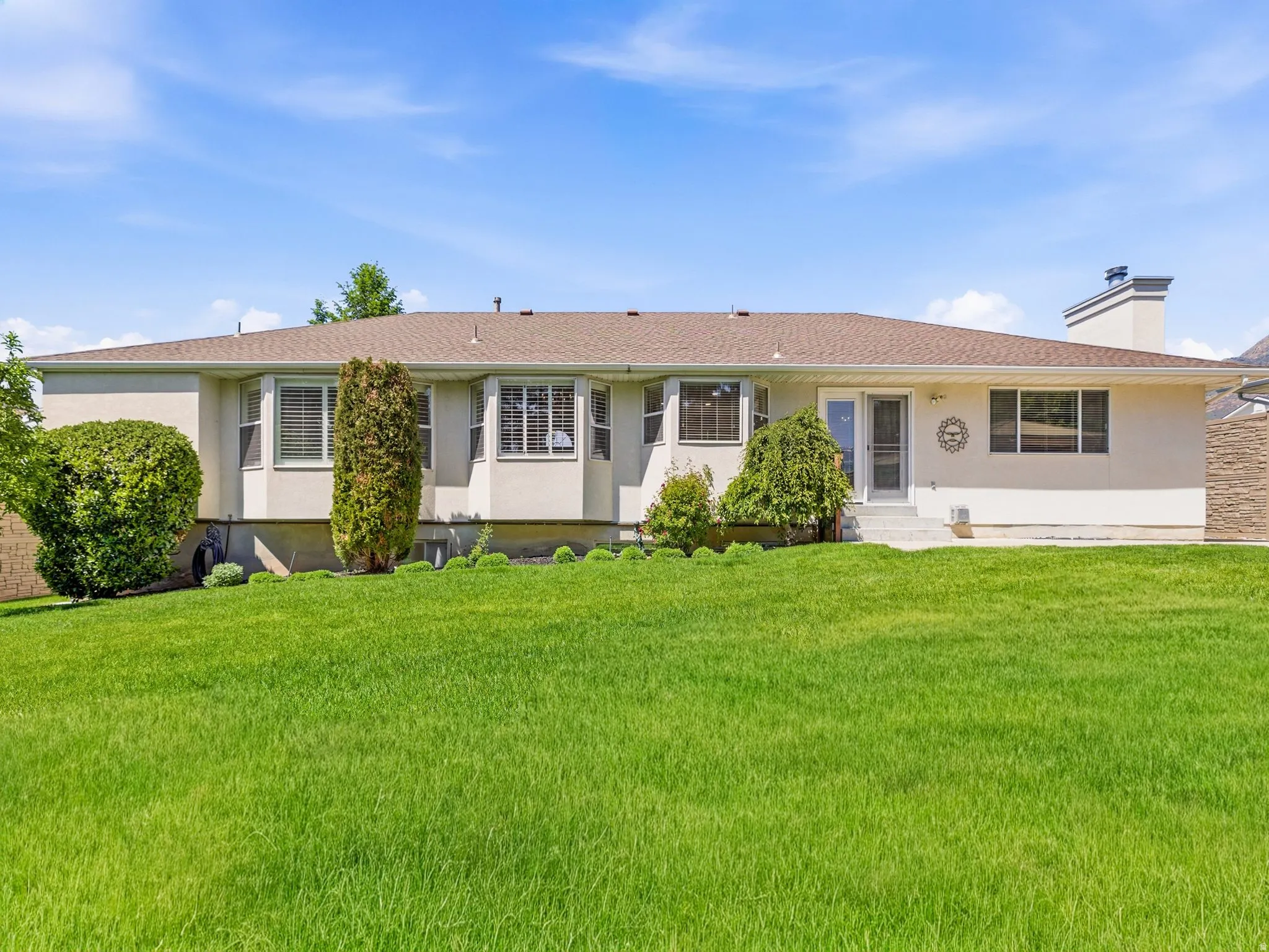 Expansive green lawn with a stucco exterior home