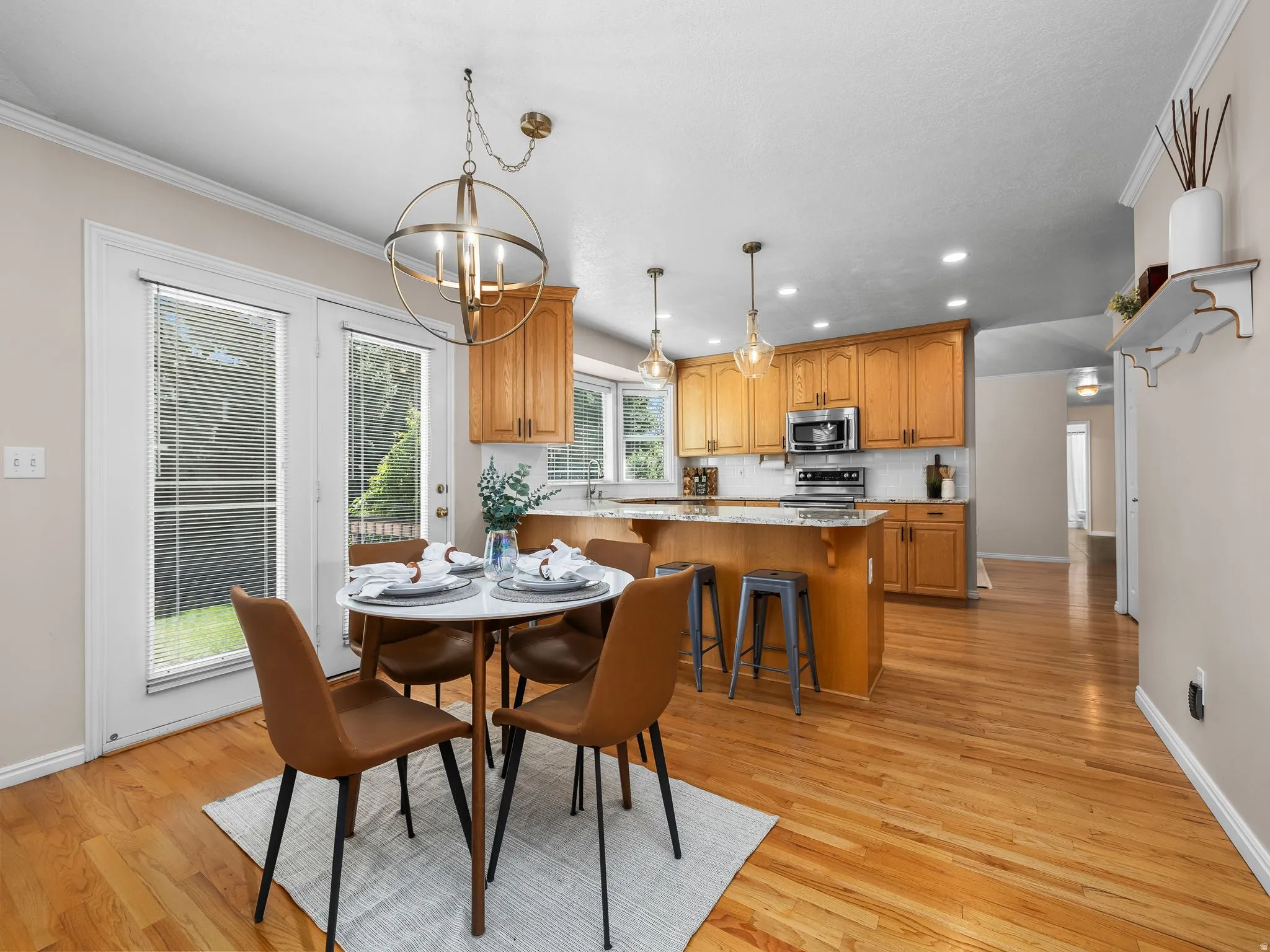 Kitchen and dining area featuring wood-finish flooring, light wood cabinetry, recessed lighting, and a kitchen island with seating