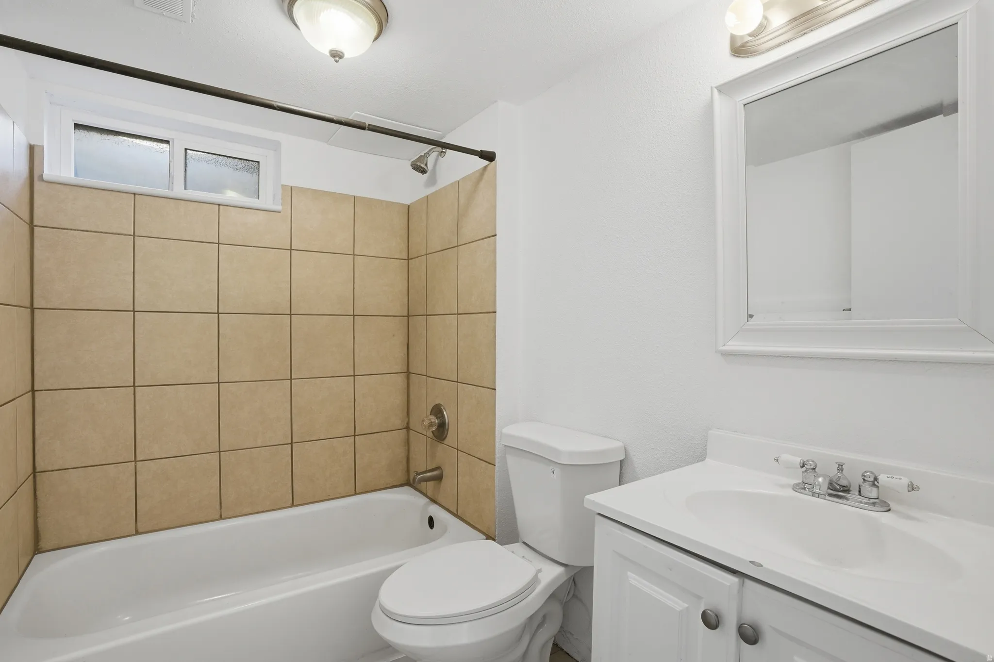 Bathroom featuring a white vanity with integrated sink, chrome-finish faucet, and a framed mirror with overhead lighting