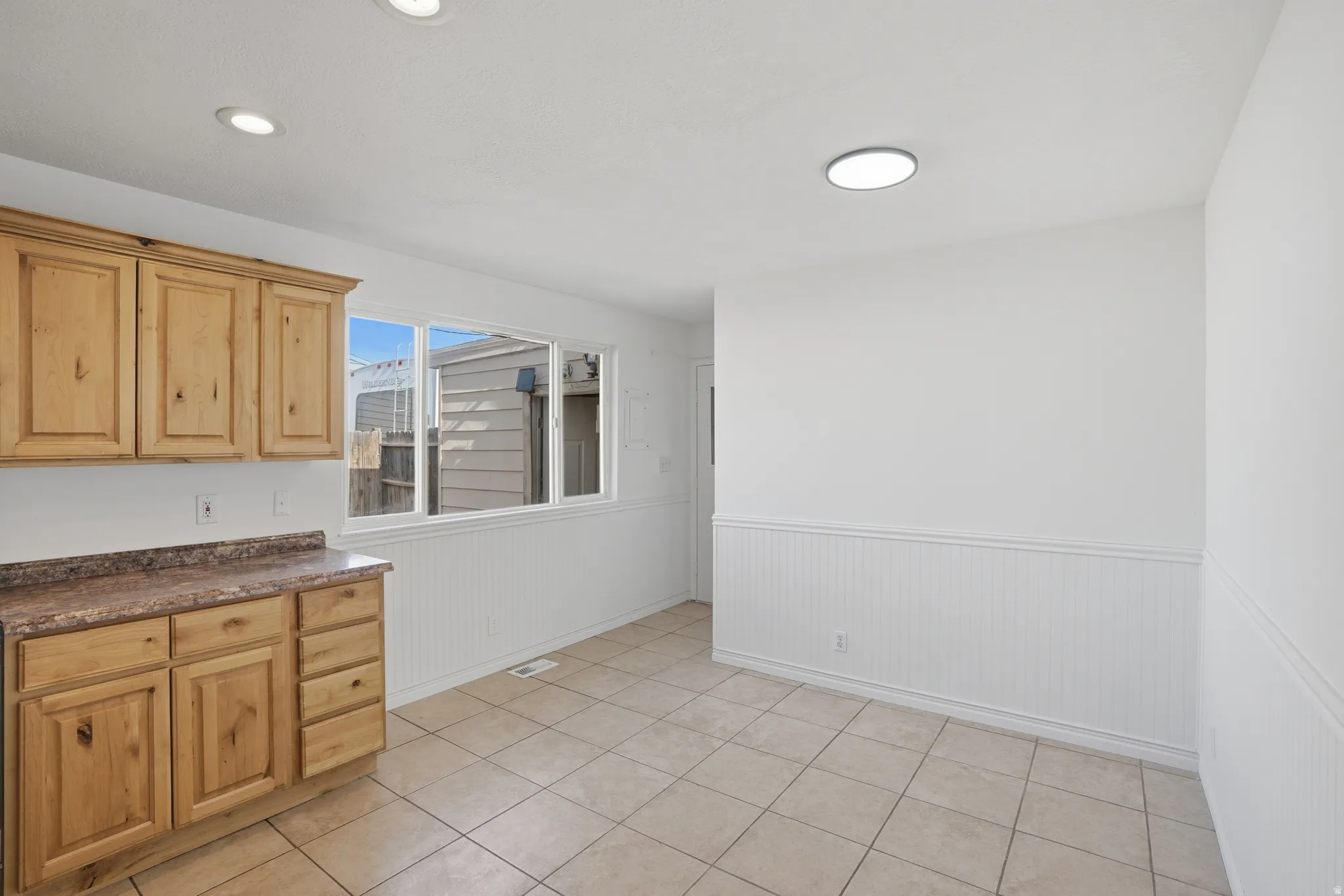 Kitchen area featuring wood cabinetry, a laminate countertop, and a tile floor