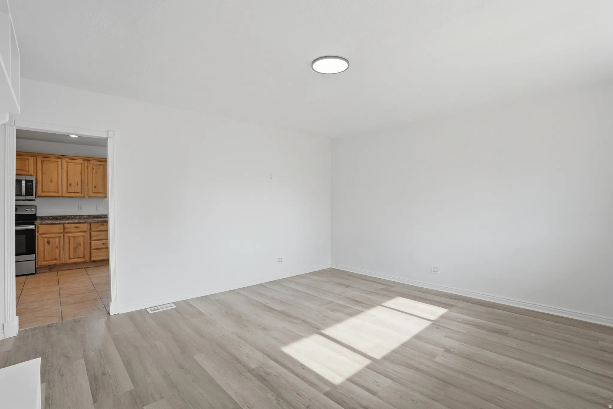 Open concept living space featuring light wood-finish flooring and a flush-mount ceiling light