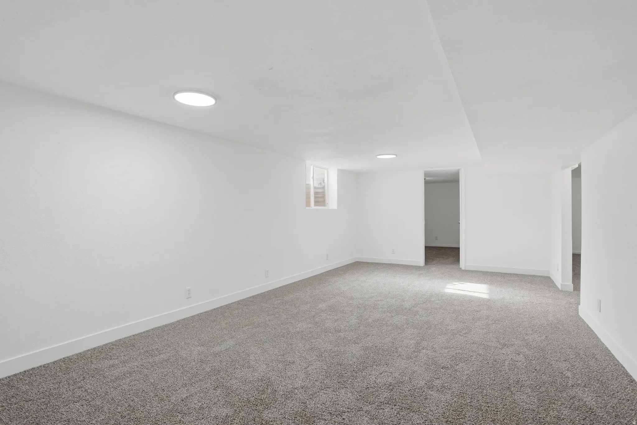Spacious room featuring light gray carpet, white painted walls, and recessed ceiling lighting