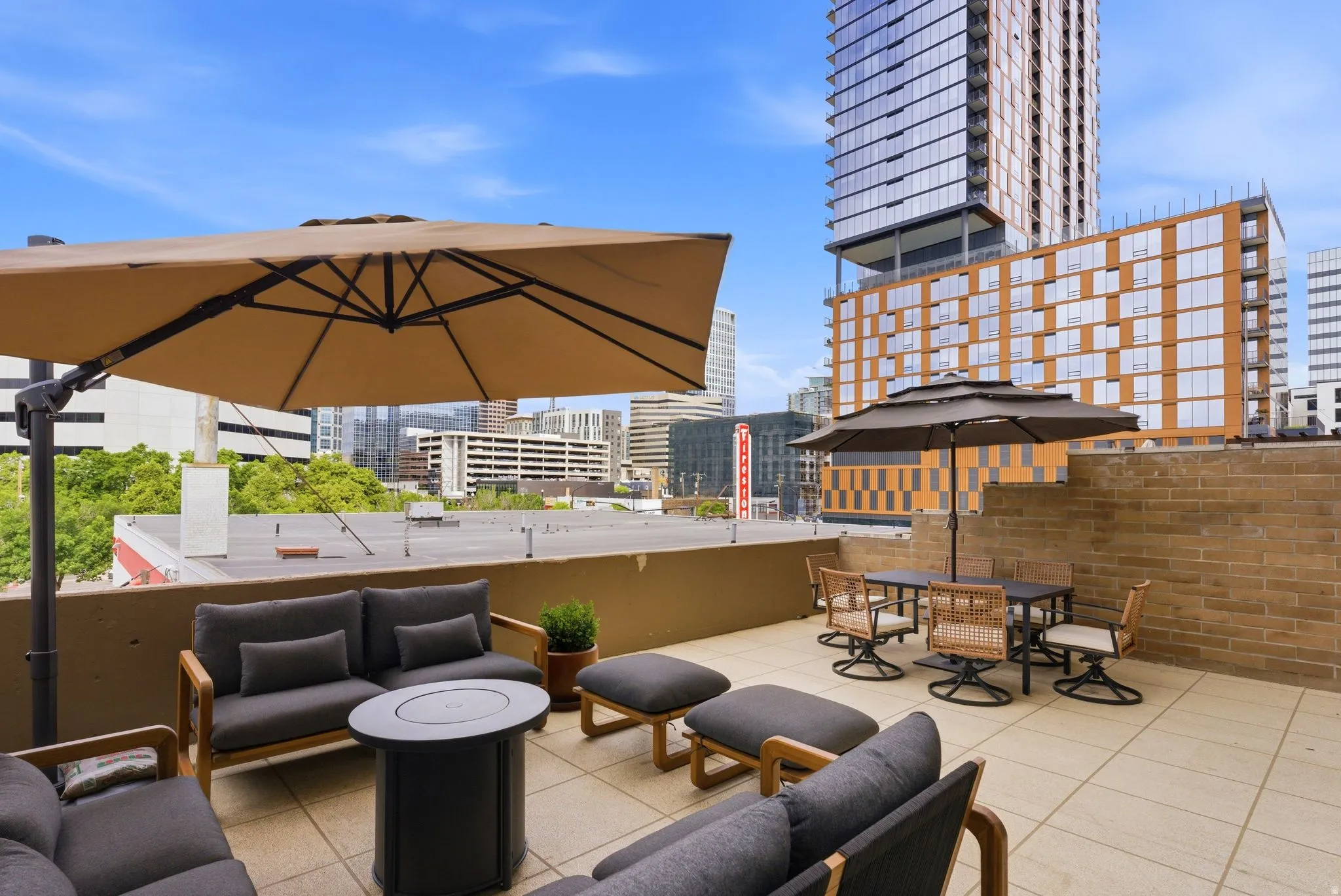 Rooftop patio featuring light-colored tile flooring, a half-height perimeter wall, and a brick accent wall