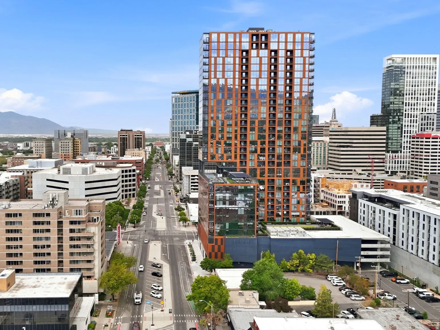 Urban streetscape with diverse architecture, including a prominent modern high-rise featuring a patterned facade and numerous windows