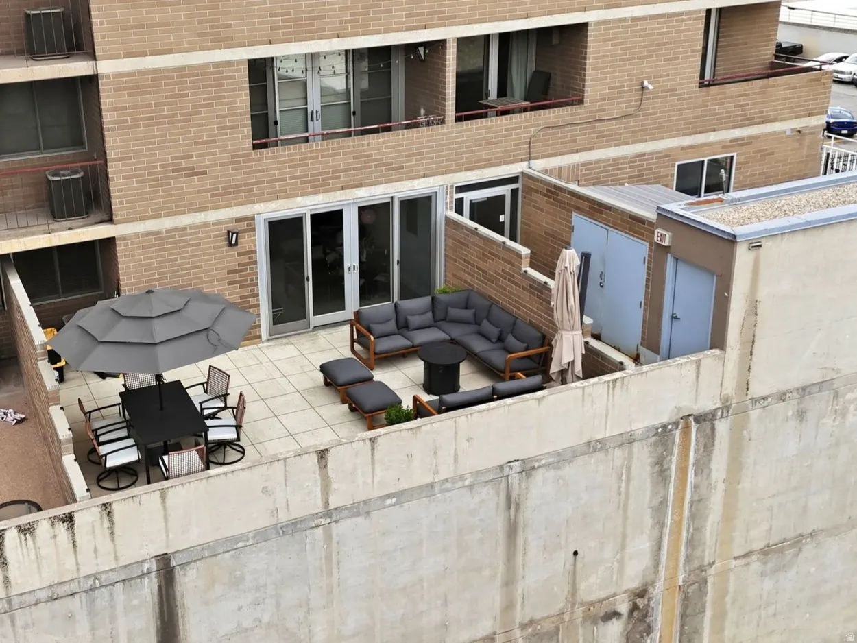 Spacious outdoor terrace featuring a large sectional seating area, a dining set with an umbrella, and direct access through a double glass door
