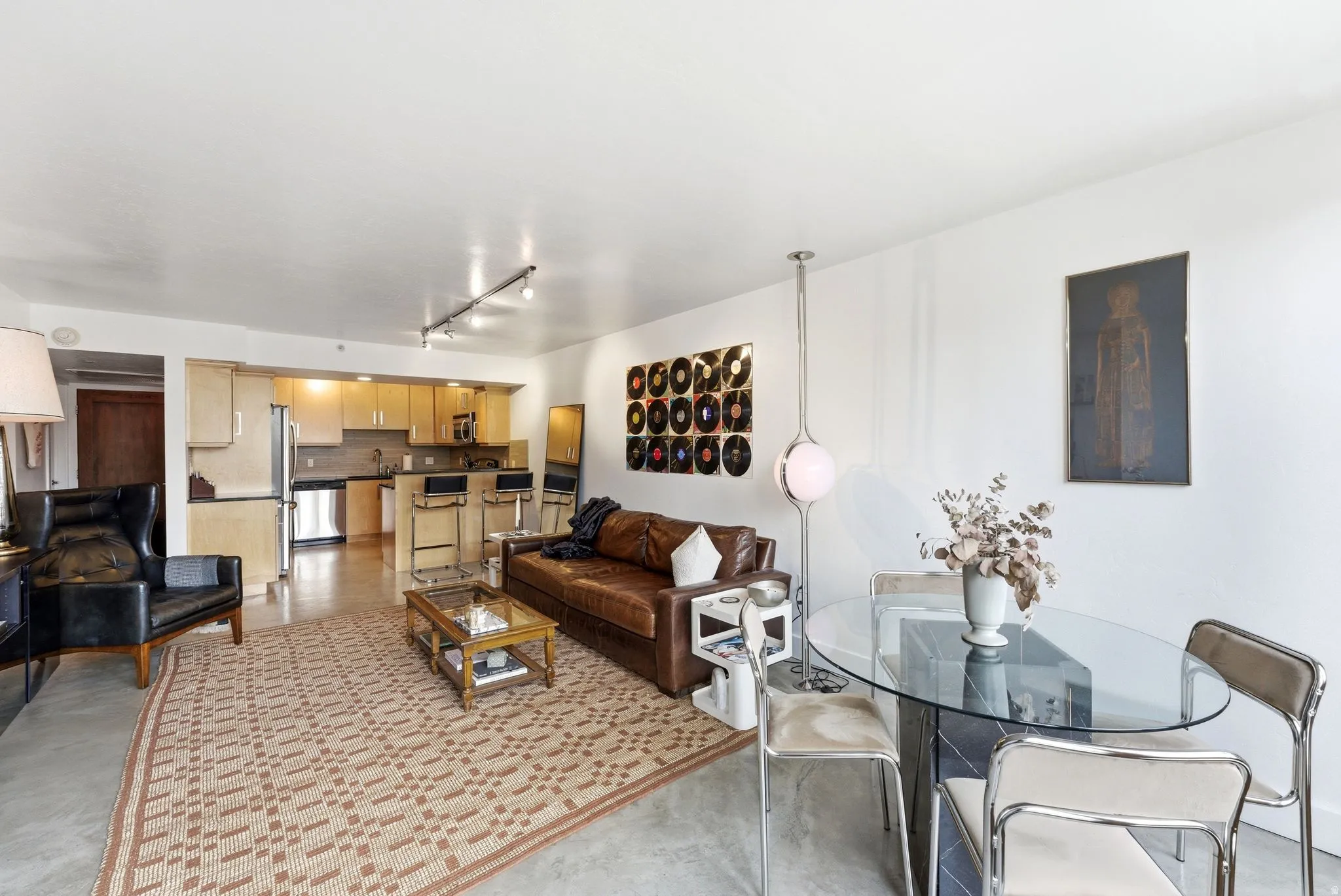 Open-concept living space featuring a kitchen with light wood cabinetry, stainless steel appliances, and a breakfast bar