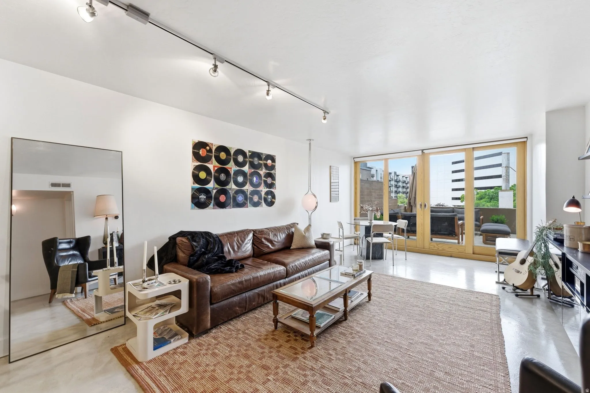 Open-concept living space featuring track lighting, light-toned flooring, and expansive glass sliding doors