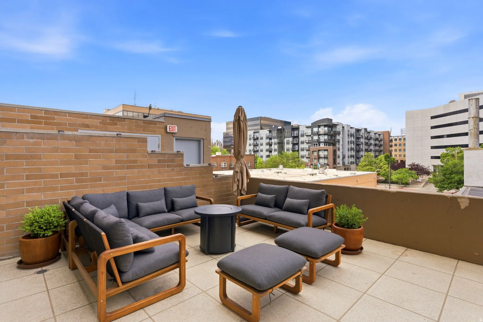 Expansive rooftop terrace featuring a tiled surface, a partial brick wall, and perimeter fencing