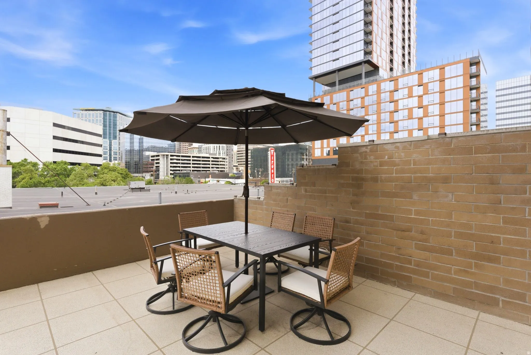 Expansive outdoor patio featuring light-toned tile flooring and a brick privacy wall