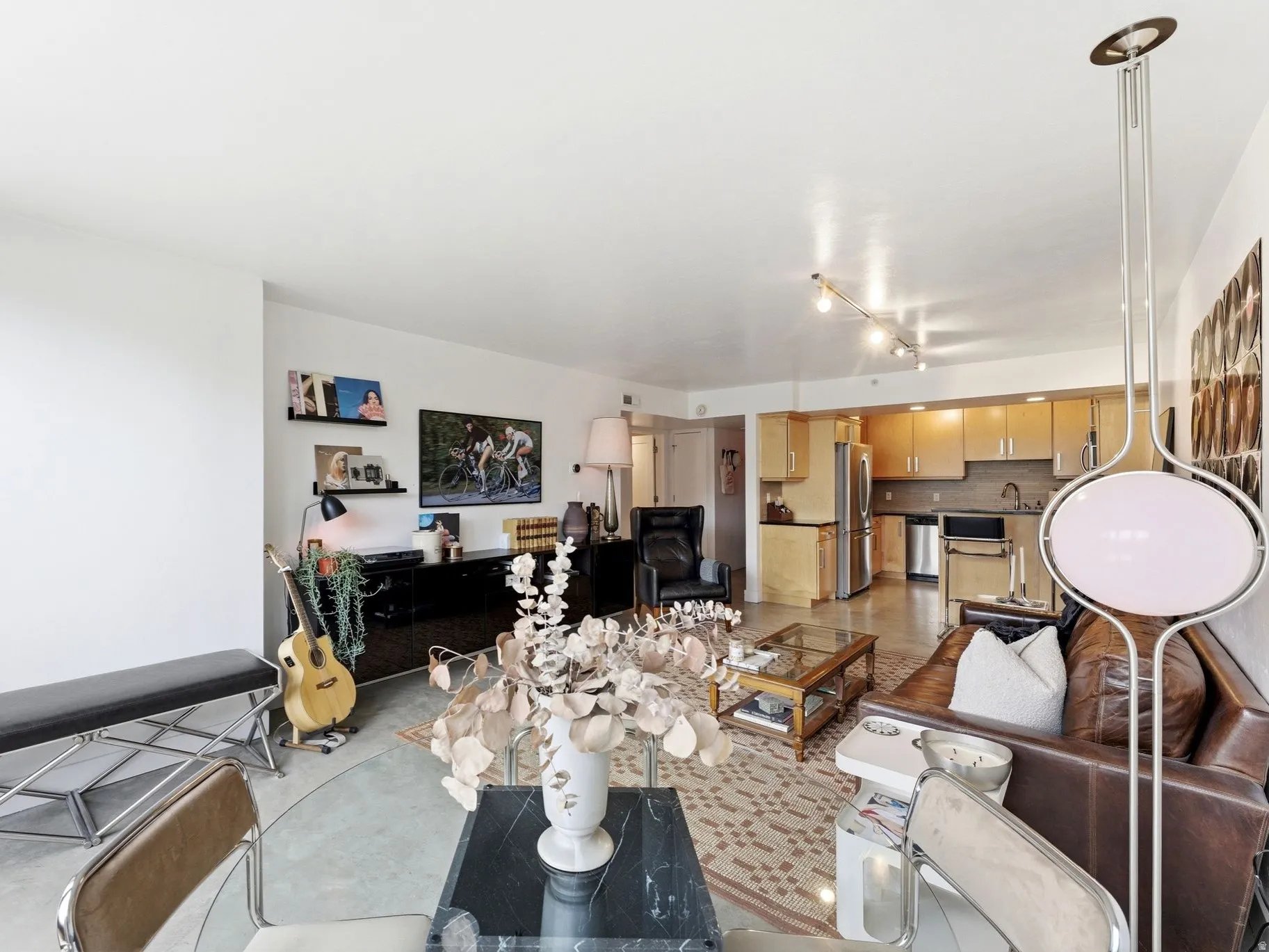 Open-concept living space featuring a full kitchen, track lighting, and hard-surface flooring