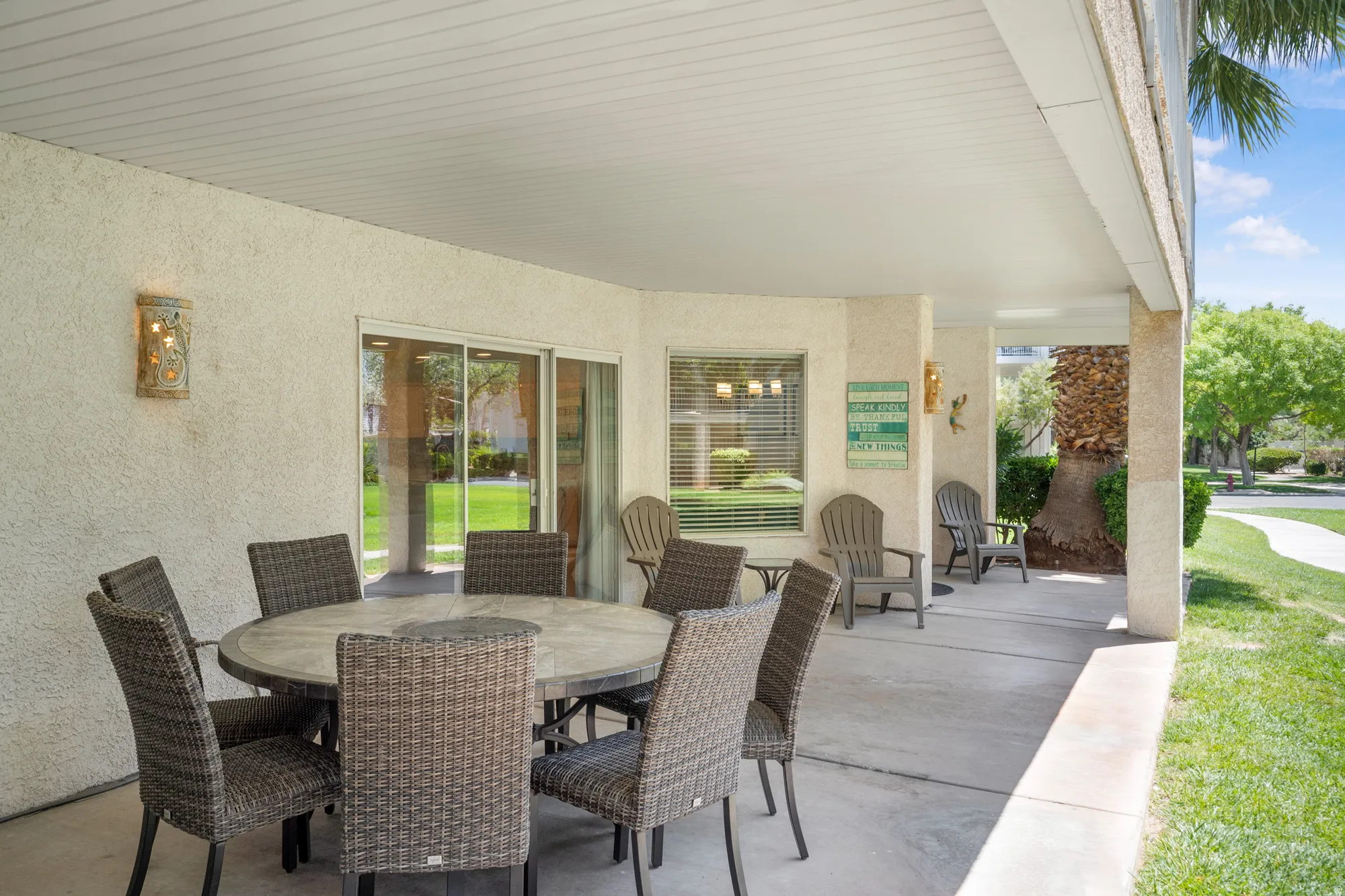 Covered patio area featuring concrete flooring, stucco exterior walls, and a slatted white ceiling