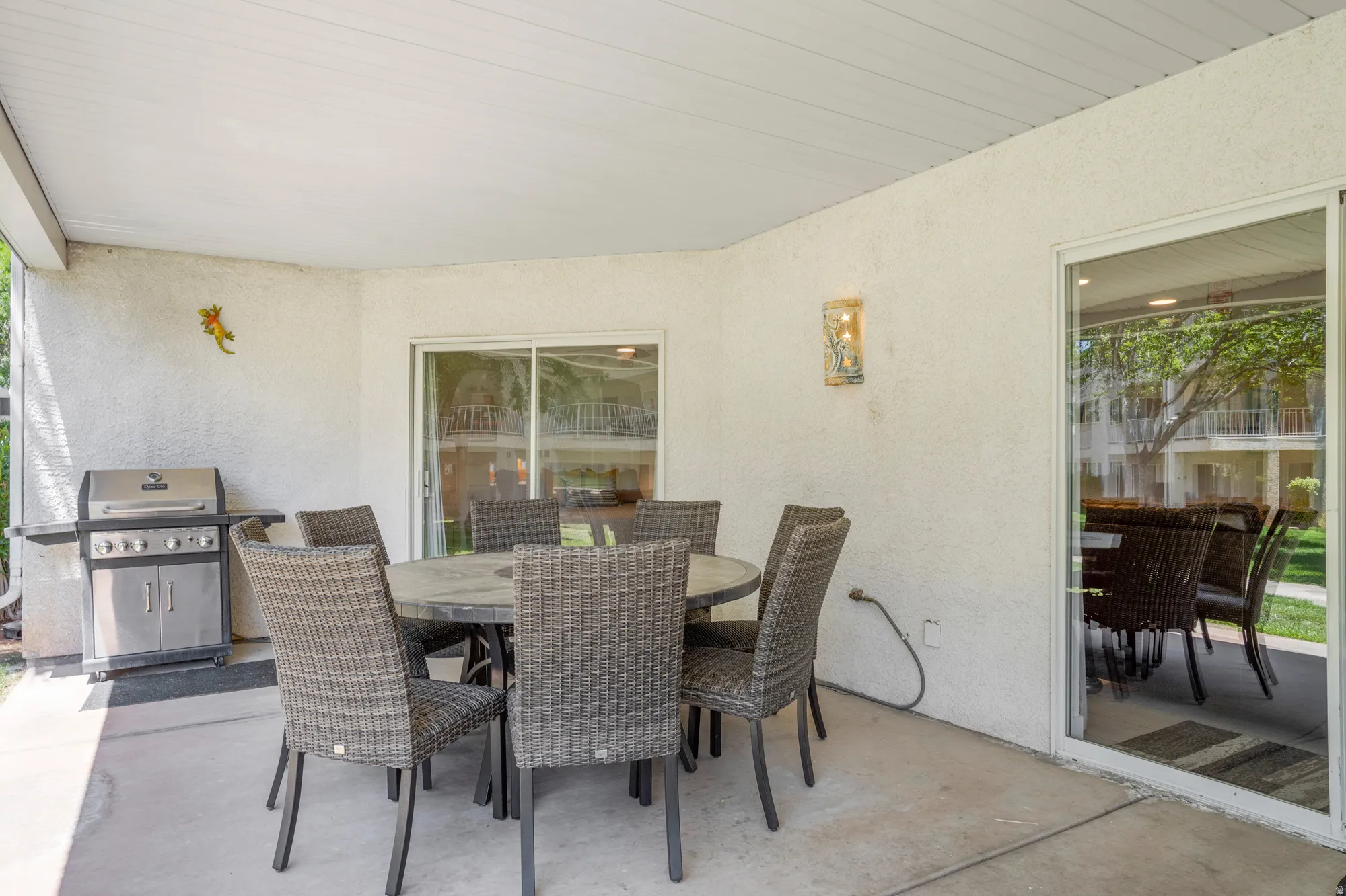 Covered patio with concrete flooring, stucco exterior, and wall-mounted light fixture