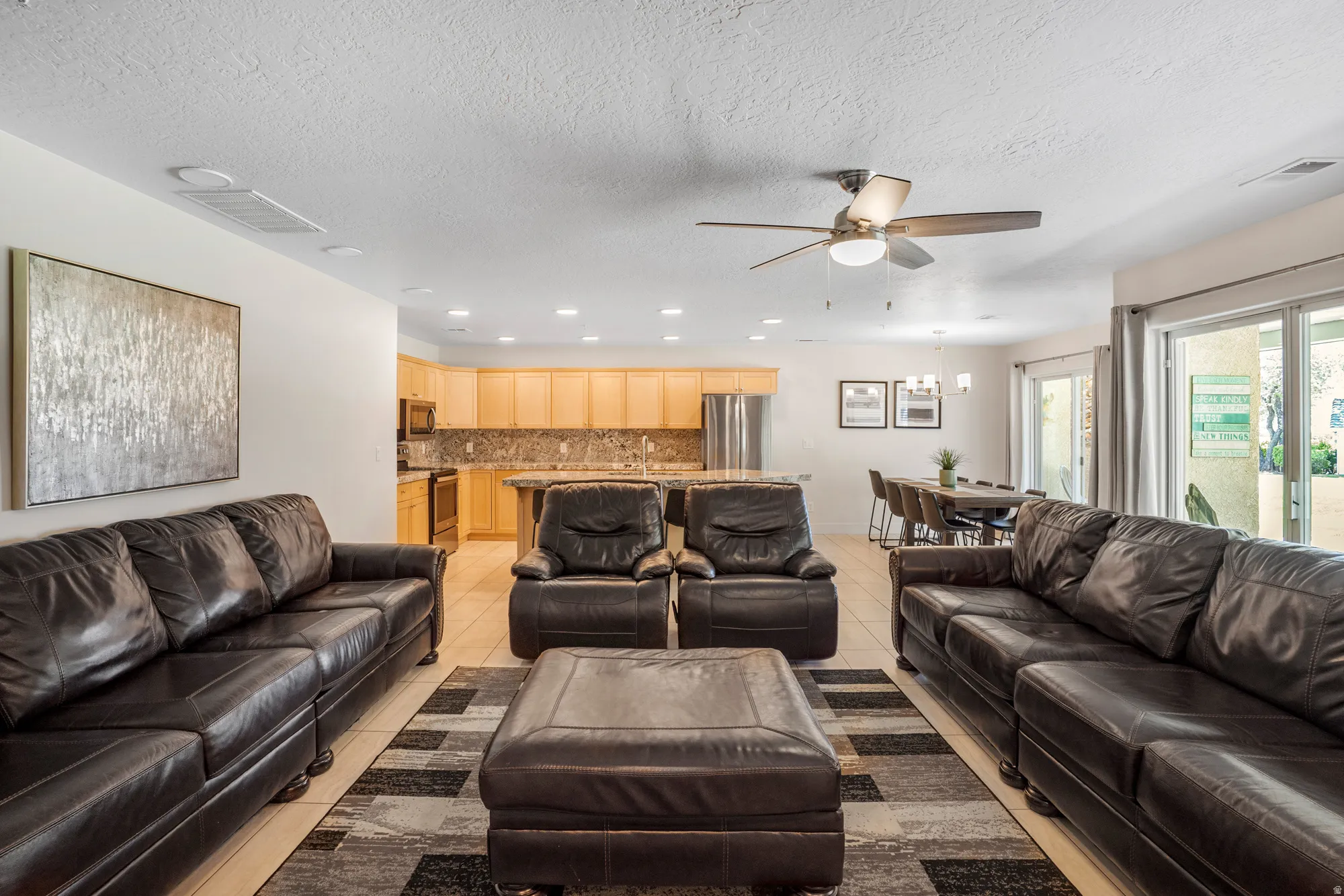 Open-concept living space featuring light-toned flooring, recessed lighting, and a ceiling fan