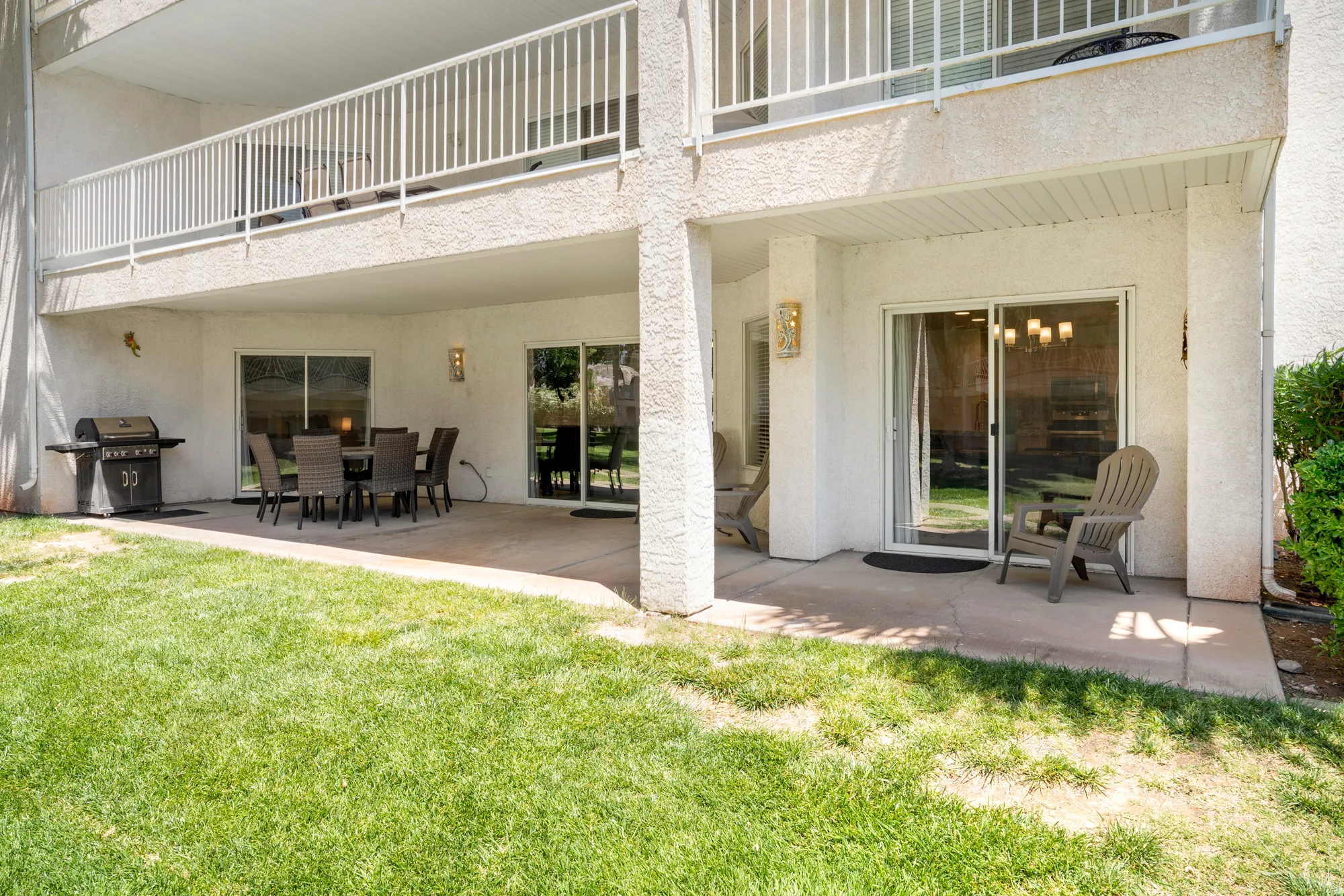 Ground-level patio with a spacious concrete surface, covered overhang, and exterior wall sconces