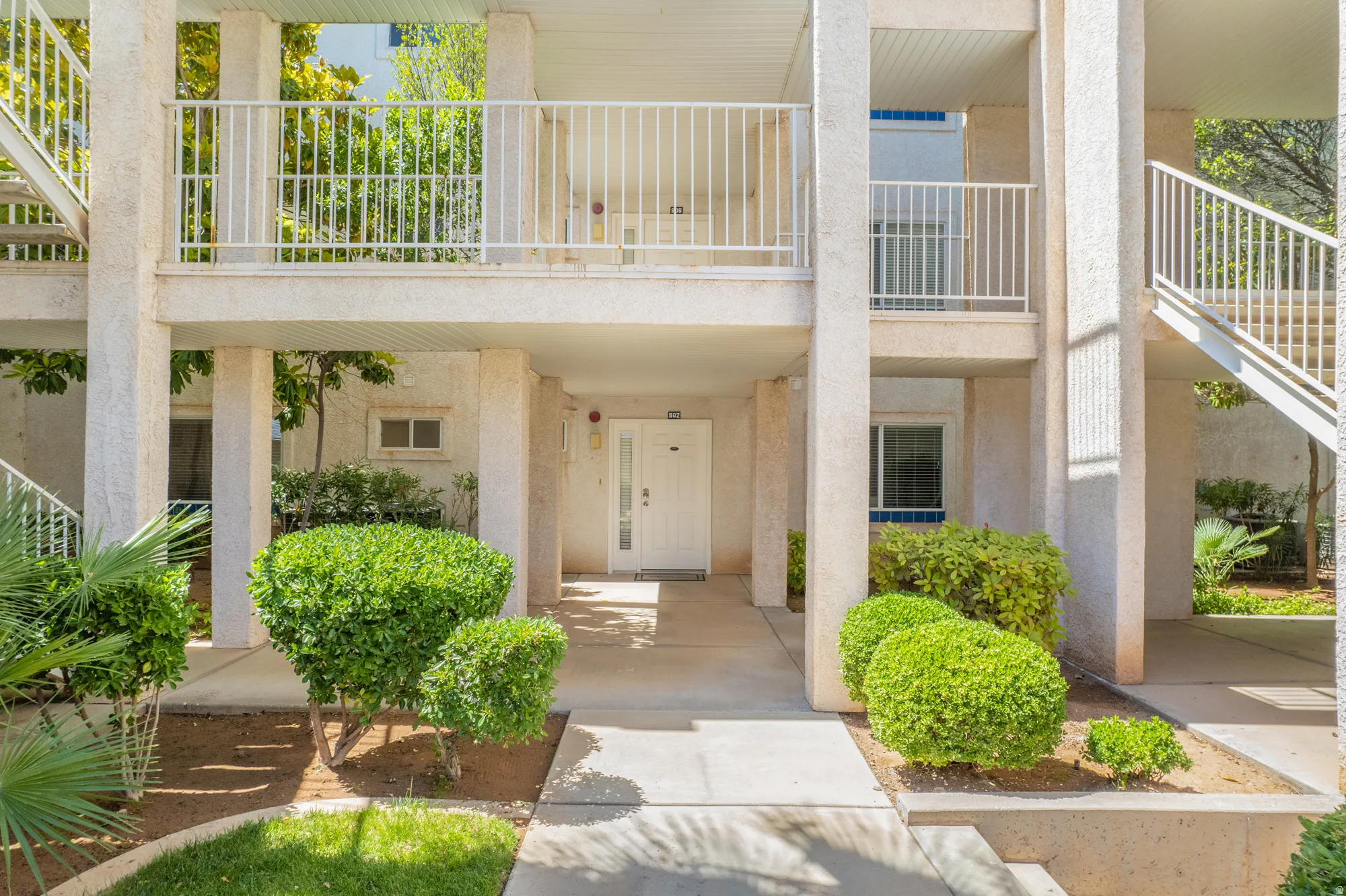 Cream-colored stucco exterior with white railings and exterior staircases