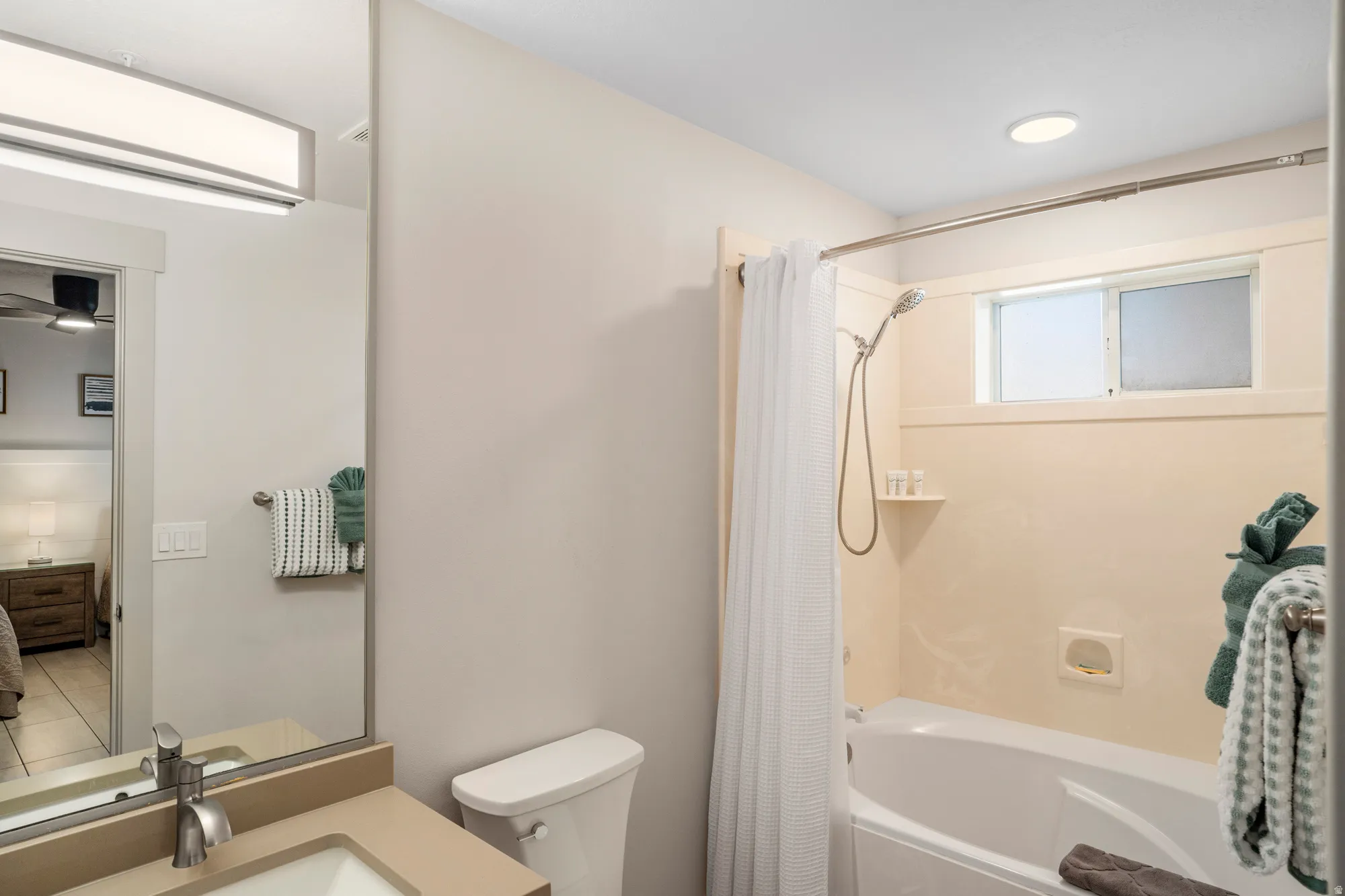 Bathroom featuring a single vanity with a solid surface countertop, an undermount sink, and a brushed nickel faucet