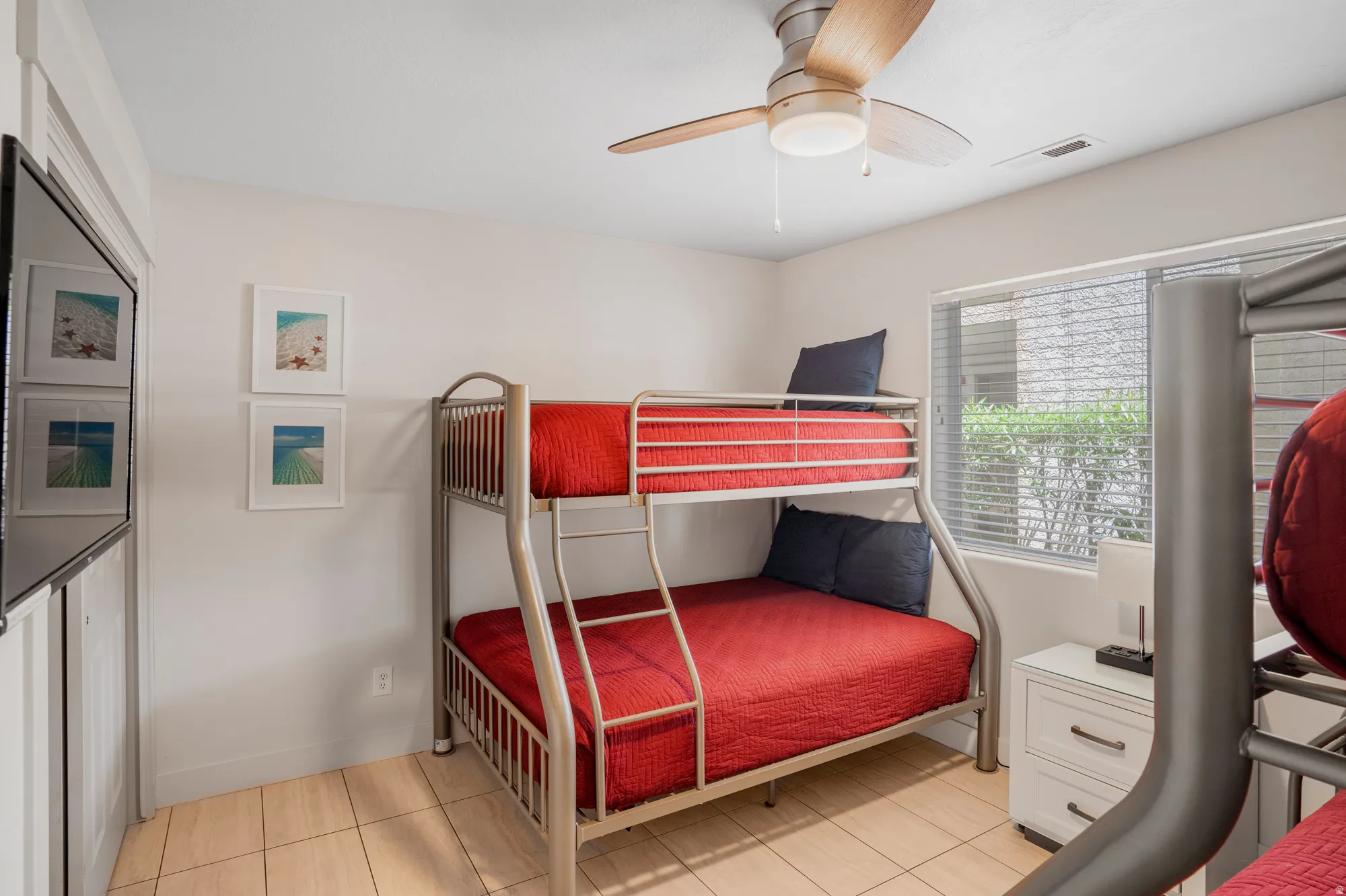 Room featuring metal bunk beds, tile flooring, and a ceiling fan with light fixture