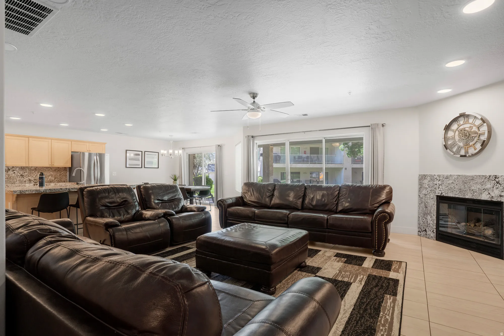 Open-concept living area featuring a corner fireplace with a stone surround, a ceiling fan, and recessed lighting