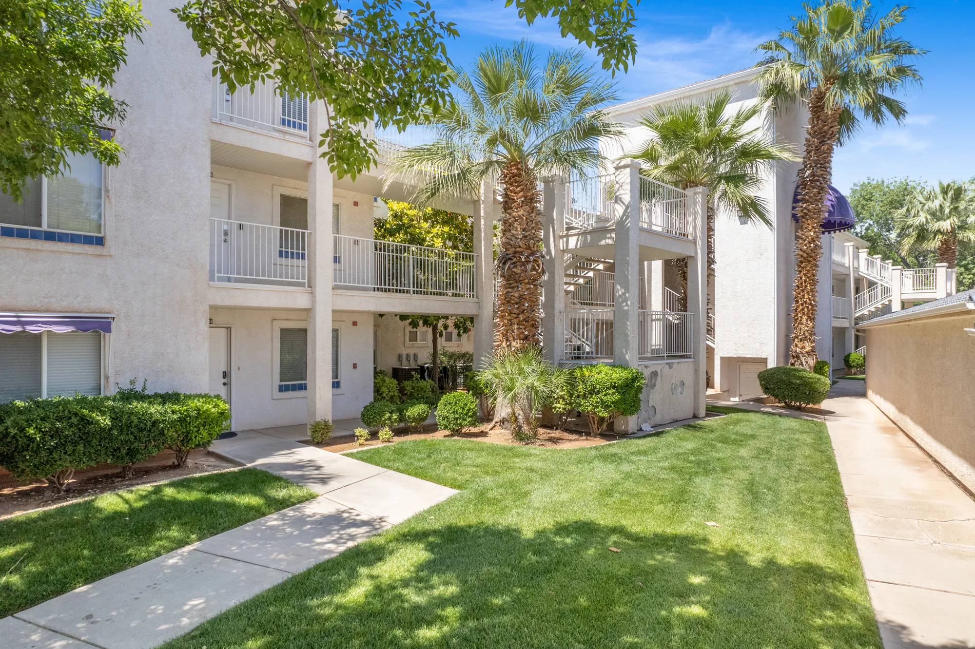 White stucco multi-story building featuring multiple balconies with white railings