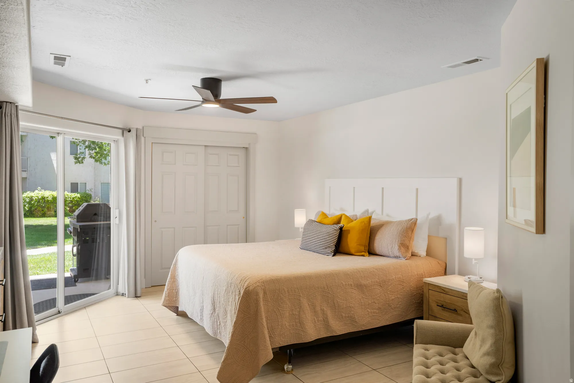 Spacious room featuring light-toned tile flooring and a ceiling fan with wood-finish blades