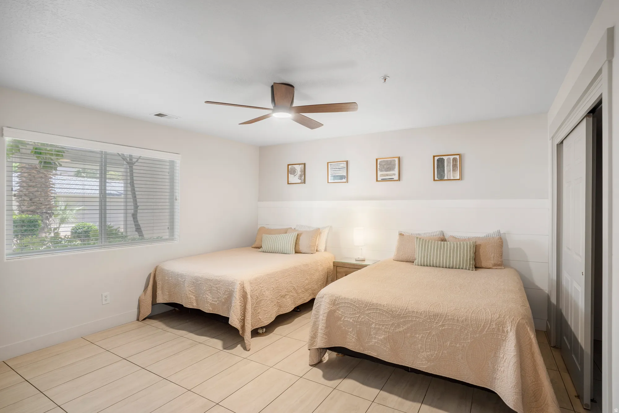 Spacious room featuring light-toned tile flooring and a ceiling fan with integrated lighting
