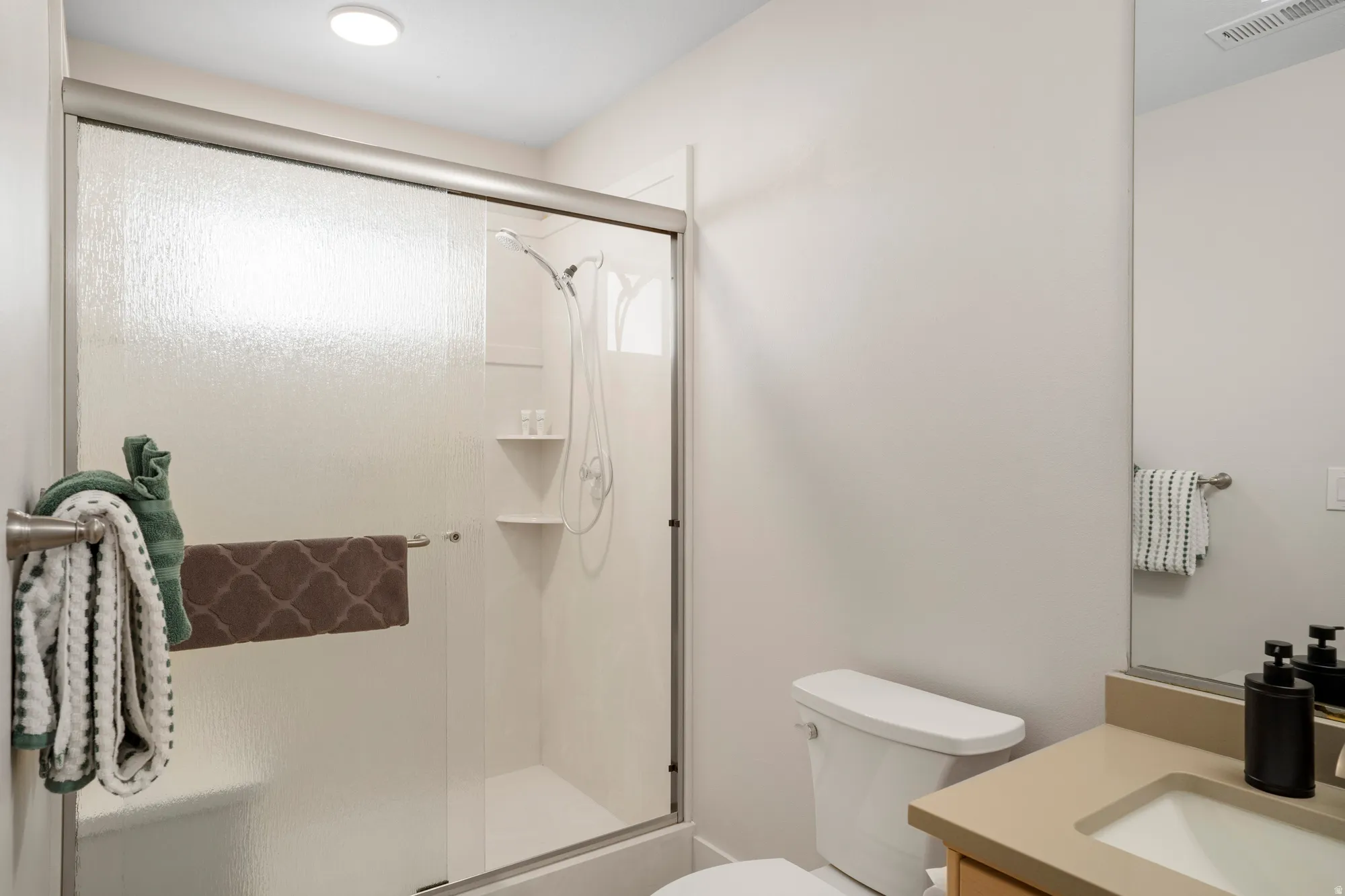 Bathroom featuring a glass-enclosed shower with integrated shelving, a built-in shower bench, and a mounted showerhead