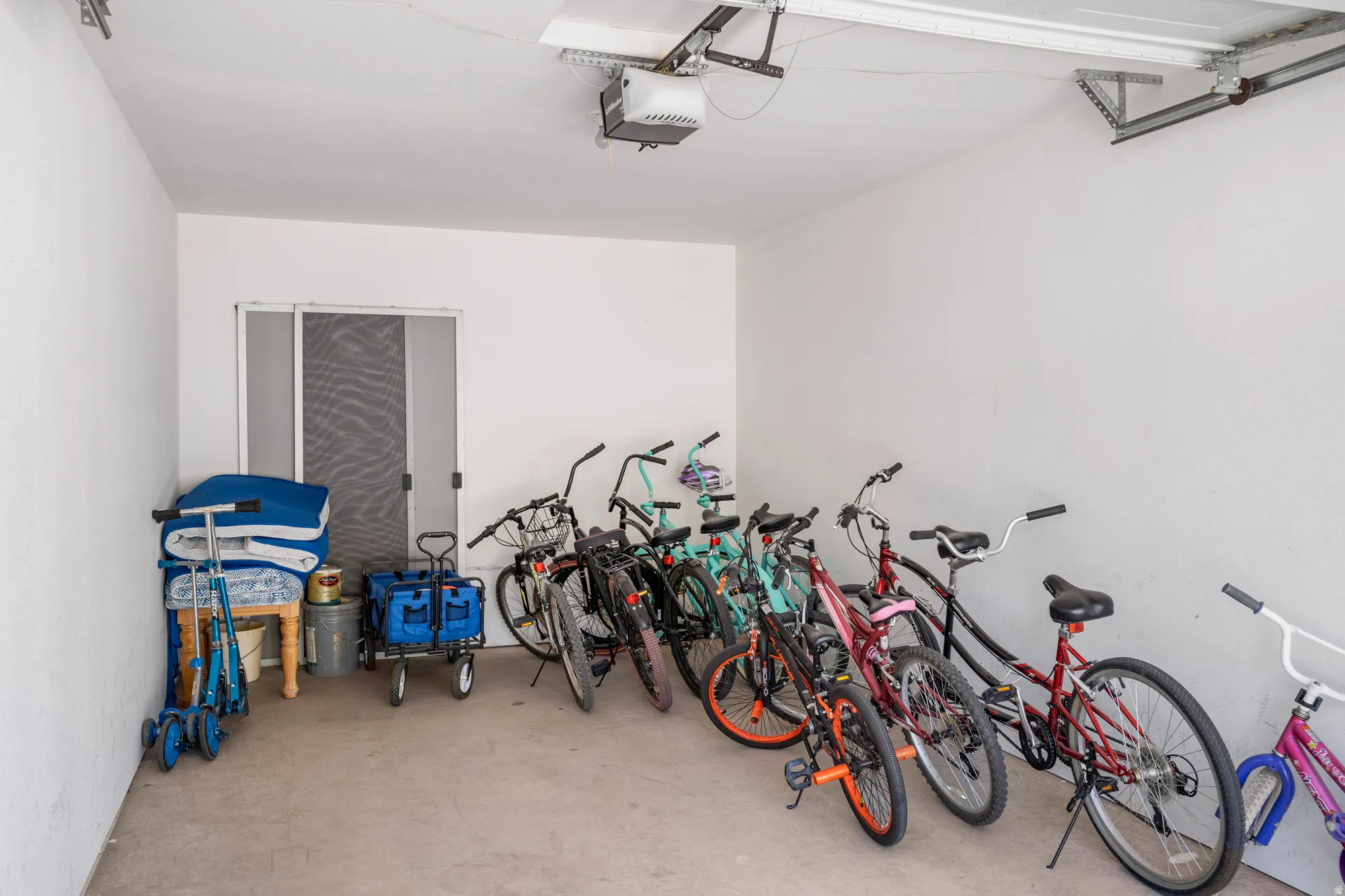 Spacious garage featuring a concrete floor, white painted walls, and an overhead garage door opener mechanism