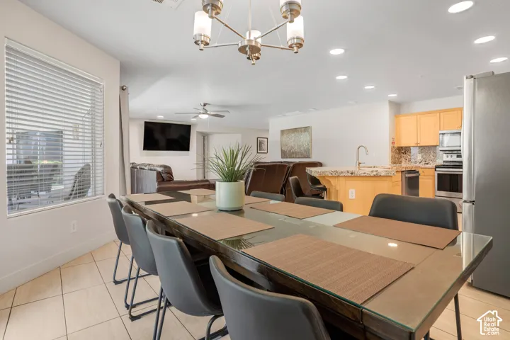 Open-concept living area featuring a dining space with tile flooring, a kitchen with light wood cabinetry and granite-finish countertops, stainless steel appliances, and recessed lighting throughout