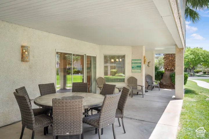 Covered patio area featuring concrete flooring, stucco exterior walls, and a slatted white ceiling