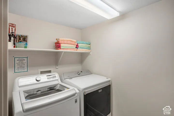 Dedicated laundry area featuring a top-load washing machine, front-load dryer, and overhead shelving for storage