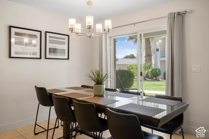 Dining area featuring wood-finish flooring, a modern chandelier with frosted glass shades, and sliding glass doors opening to a green space