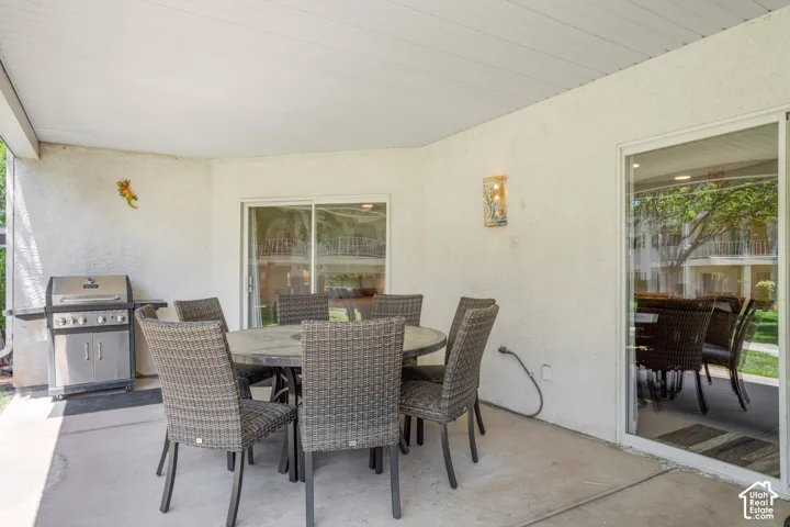 Covered patio with concrete flooring, stucco exterior, and wall-mounted light fixture