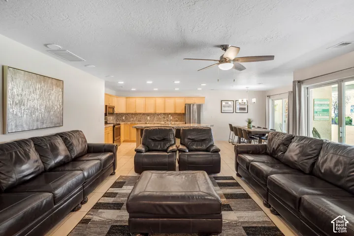 Open-concept living space featuring light-toned flooring, recessed lighting, and a ceiling fan