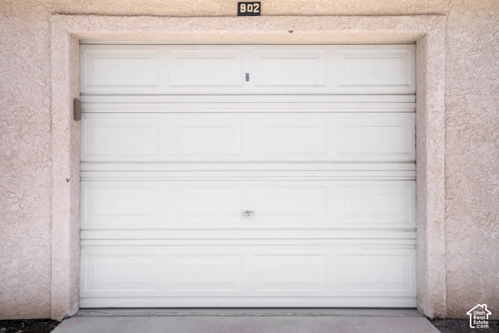 White paneled garage door with a textured stucco surround and integrated address number