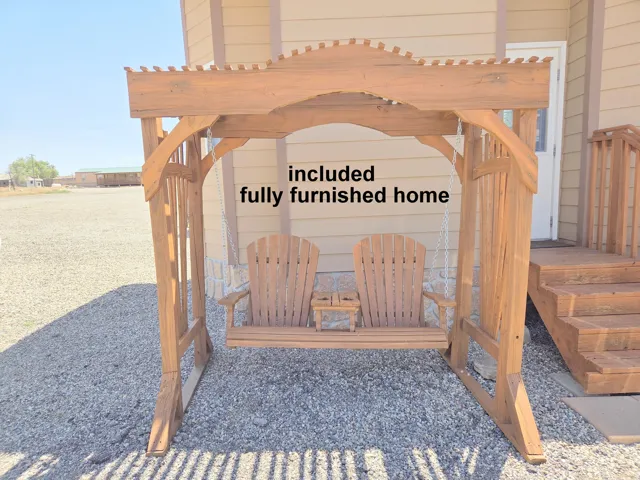 Wooden porch swing with Adirondack-style seating, set on a gravel surface