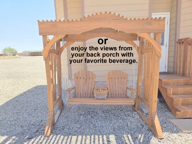 Outdoor swing with an integrated pergola structure, two Adirondack-style seats, a central built-in table, and a gravel ground surface