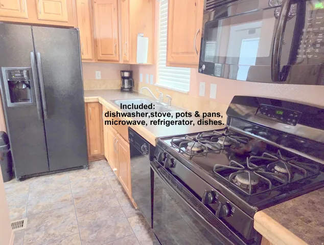 Kitchen featuring wood cabinetry, stone-finish countertops, tile flooring, and integrated black appliances